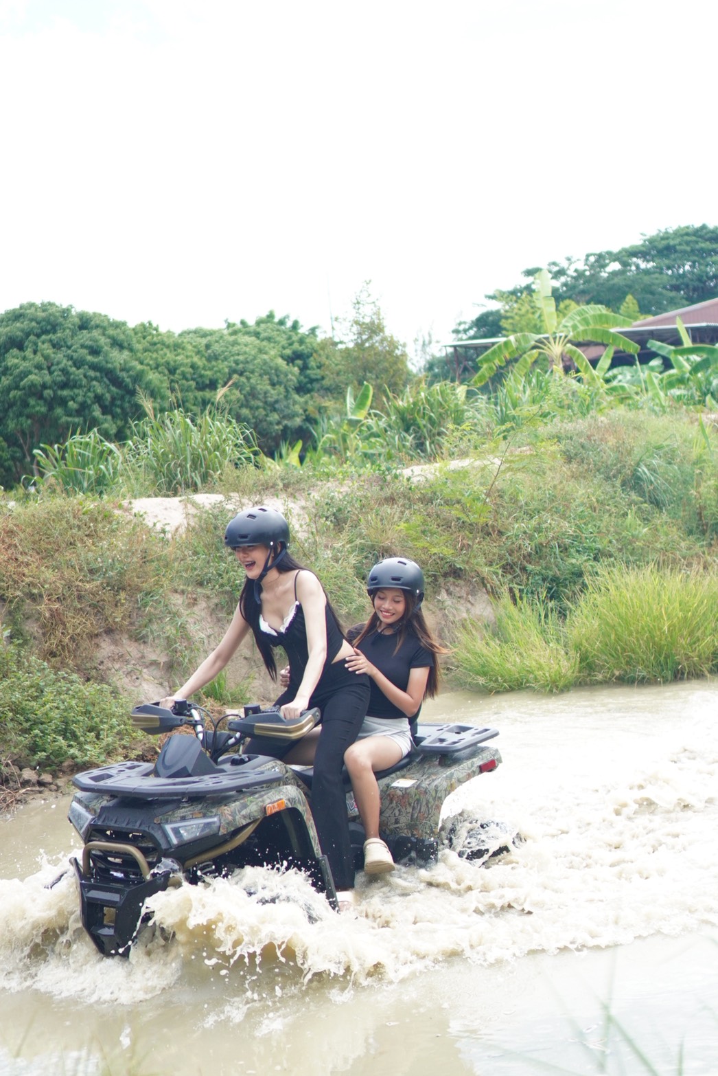 Two guests riding an ATV through a water crossing